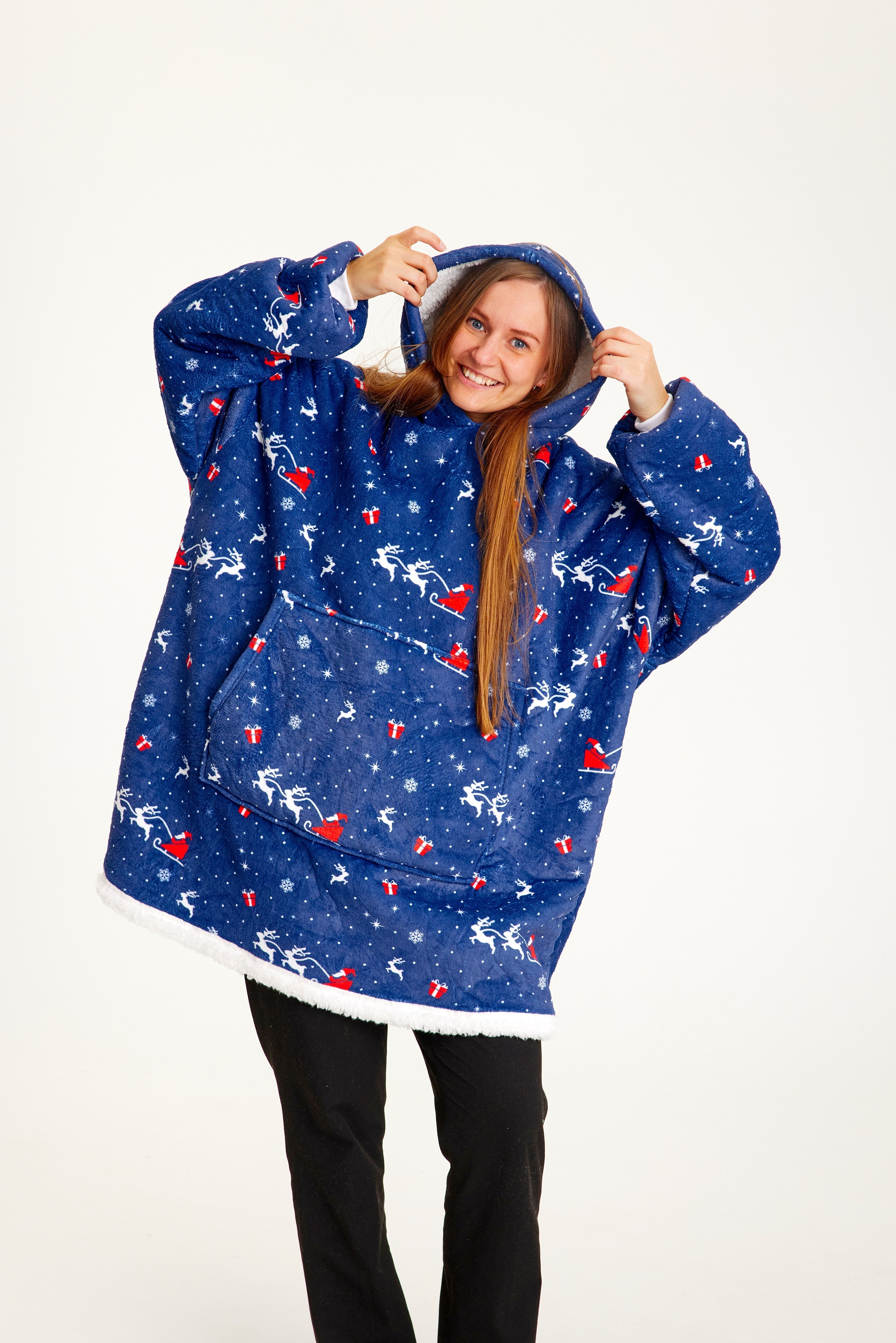 Een lachende vrouw in een blauwe kersttrui met kerstopdruk.